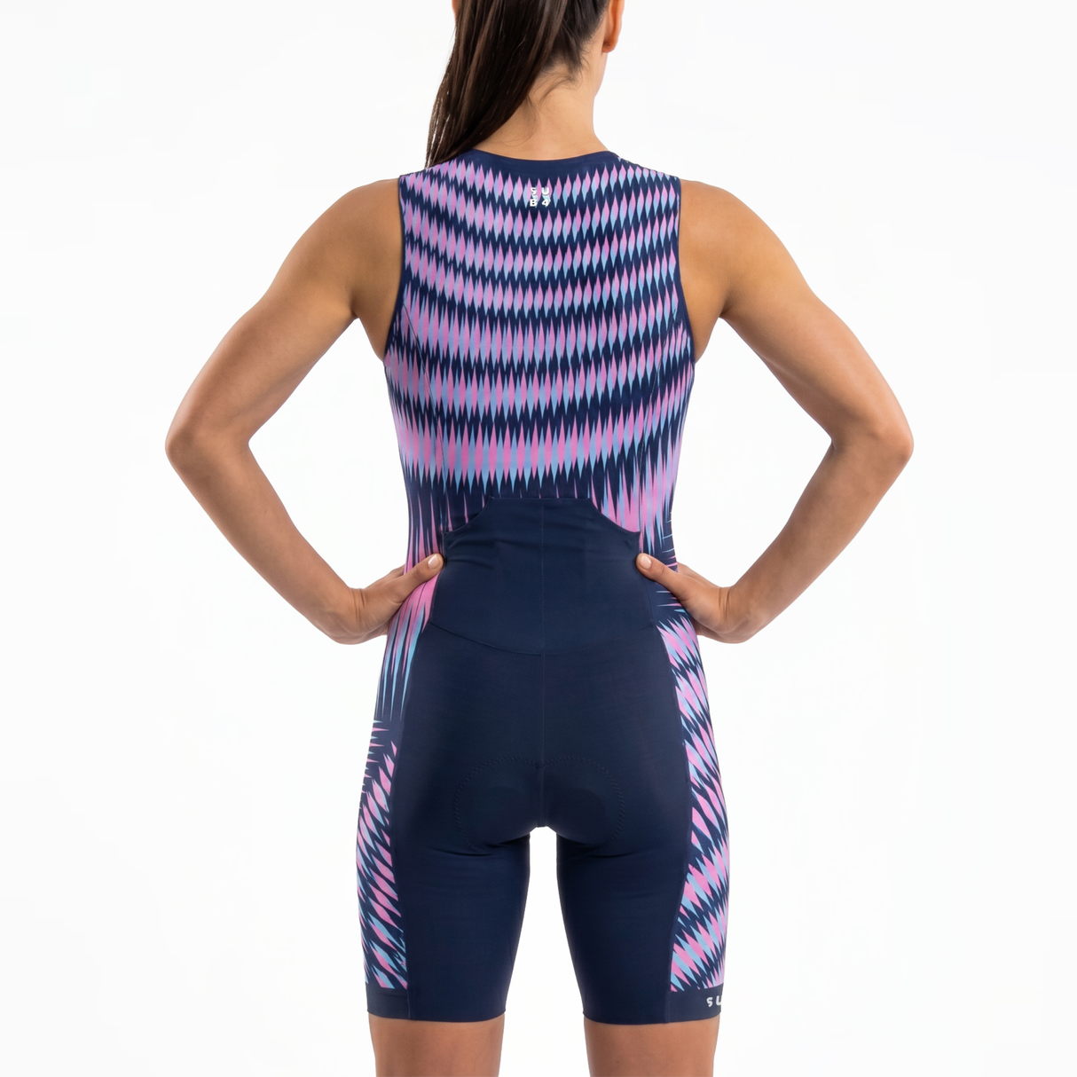 Rear view of a woman wearing a sleeveless Triathlon one-piece suit with a blue base and pink and purple wavy geometric pattern, against a plain white background.