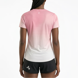 Back view of woman wearing a pink and white gradient running t-shirt and black running shorts on a white background