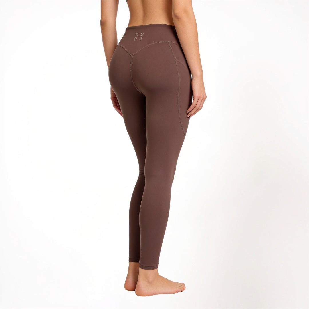 Brown athletic gym yoga leggings worn by a person on a white background