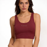 Woman wearing a maroon red sports bra with 'SUNA' branding on a white background
